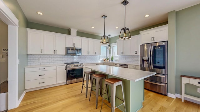 577 Keefe Ct NW, Eyota, MN 55934 - kitchen with appliances with stainless steel finishes, white cabinets, light wood-style floors, a kitchen breakfast bar, and decorative backsplash