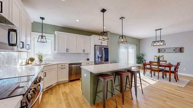 577 Keefe Ct NW, Eyota, MN 55934 - kitchen featuring appliances with stainless steel finishes, a sink, decorative backsplash, light wood-type flooring, and white cabinetry