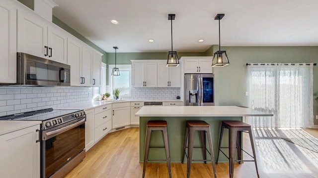 577 Keefe Ct NW, Eyota, MN 55934 - kitchen with stainless steel appliances, a breakfast bar, white cabinets, backsplash, and recessed lighting