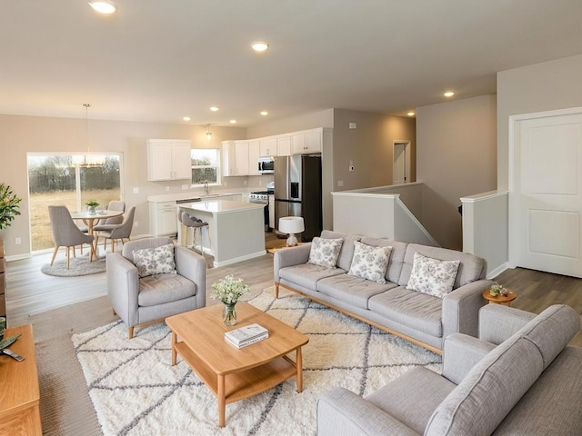 living area with light wood-style flooring, recessed lighting, a chandelier, and baseboards