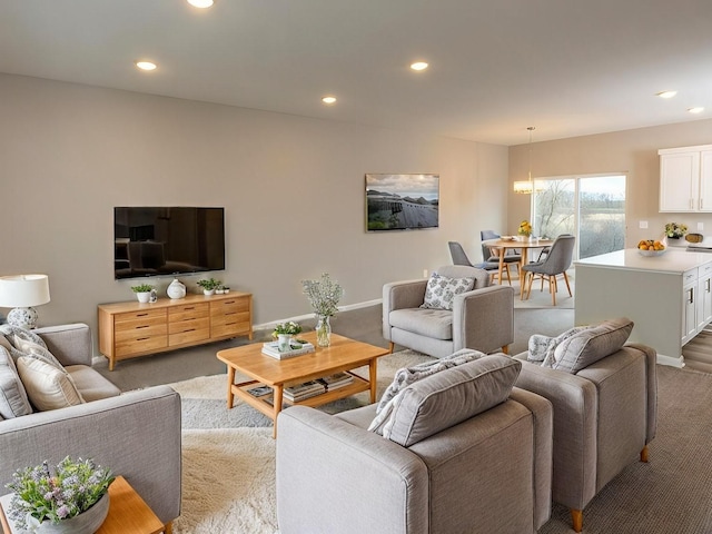 carpeted living area with recessed lighting, baseboards, and a chandelier