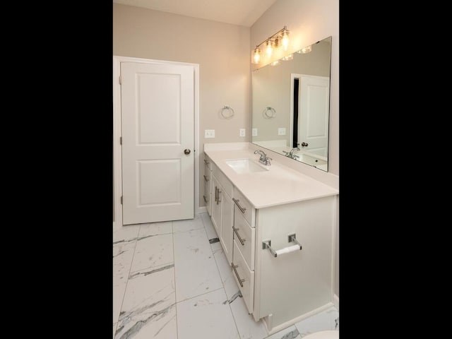 bathroom featuring marble look tile flooring, vanity, and baseboards