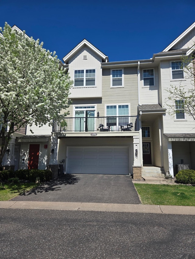 townhome / multi-family property with a balcony, driveway, a garage, and board and batten siding