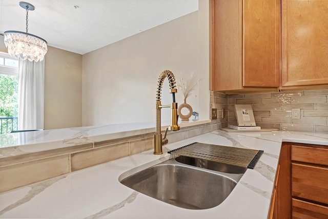 11852 Emery Village Dr N Unit 3302, Champlin, MN 55316 - kitchen featuring a sink, tasteful backsplash, light stone counters, decorative light fixtures, and a chandelier