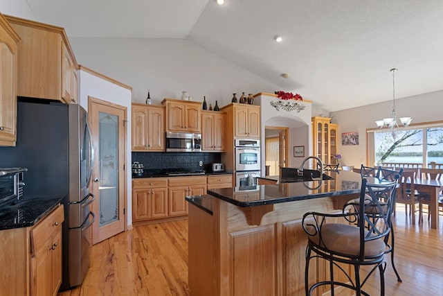 46463 Cambridge Dr, Stanchfield, MN 55080 - kitchen with stainless steel appliances, vaulted ceiling, a kitchen breakfast bar, light wood-style flooring, and backsplash