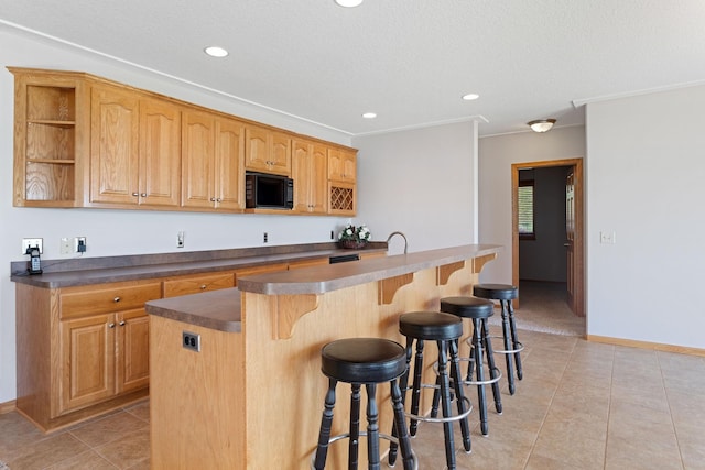 46463 Cambridge Dr, Stanchfield, MN 55080 - kitchen featuring black microwave, light tile patterned floors, recessed lighting, dark countertops, and a breakfast bar