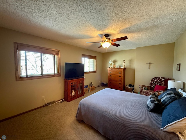 bedroom with ceiling fan, light carpet, a textured ceiling, and baseboards