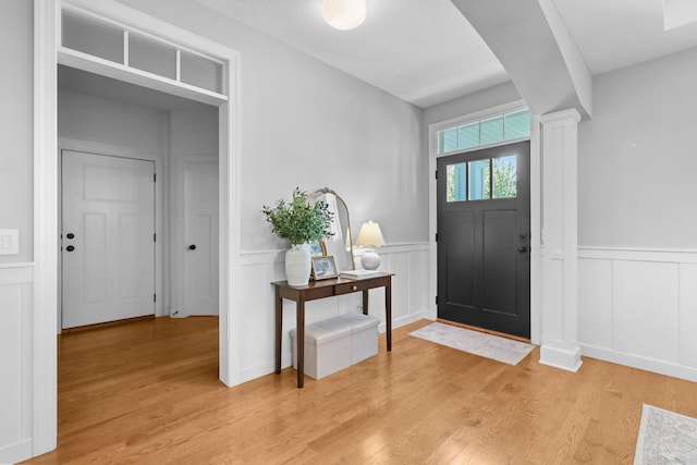 11464 Wagon Wheel Curv, Woodbury, MN 55129 - entrance foyer featuring light wood-style flooring, a decorative wall, a wainscoted wall, ornate columns, and arched walkways