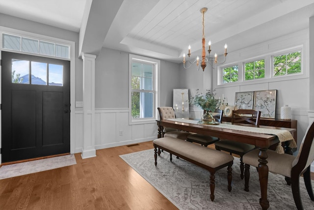 11464 Wagon Wheel Curv, Woodbury, MN 55129 - dining area with a chandelier, light wood-style flooring, a decorative wall, a raised ceiling, and wainscoting