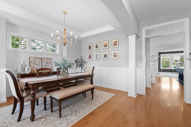 11464 Wagon Wheel Curv, Woodbury, MN 55129 - dining room with a chandelier, light wood-style floors, a wainscoted wall, a raised ceiling, and decorative columns