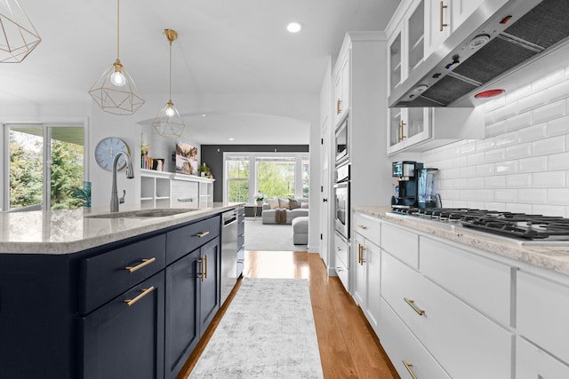 11464 Wagon Wheel Curv, Woodbury, MN 55129 - kitchen featuring under cabinet range hood, a sink, open floor plan, appliances with stainless steel finishes, and white cabinetry