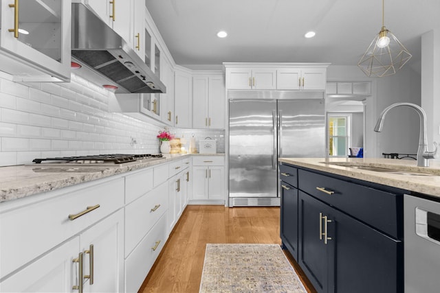 11464 Wagon Wheel Curv, Woodbury, MN 55129 - kitchen featuring stainless steel appliances, under cabinet range hood, a sink, white cabinetry, and glass insert cabinets