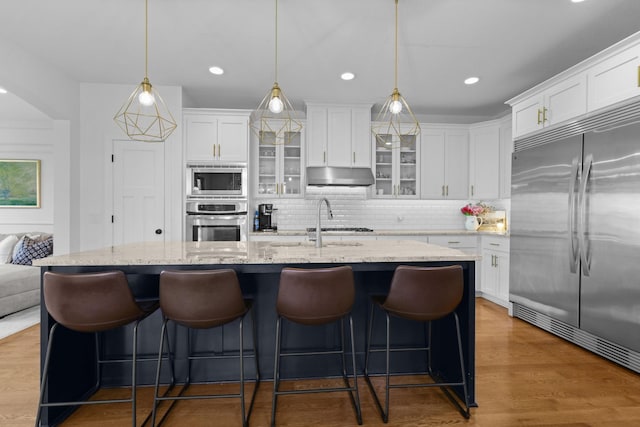 11464 Wagon Wheel Curv, Woodbury, MN 55129 - kitchen featuring built in appliances, under cabinet range hood, white cabinets, and recessed lighting