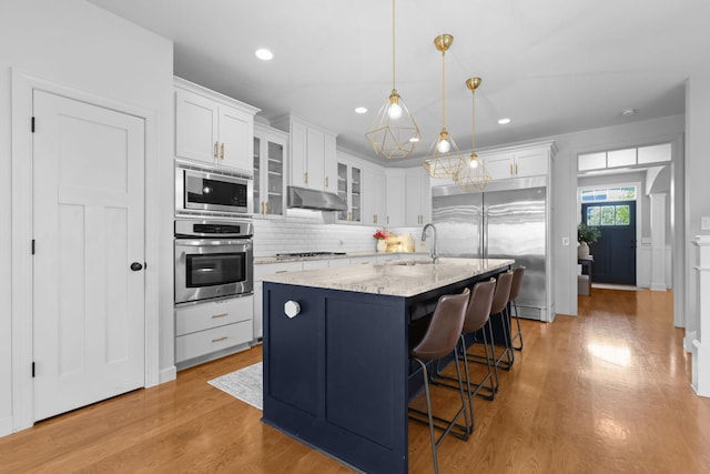 11464 Wagon Wheel Curv, Woodbury, MN 55129 - kitchen featuring built in appliances, a sink, under cabinet range hood, white cabinetry, and recessed lighting