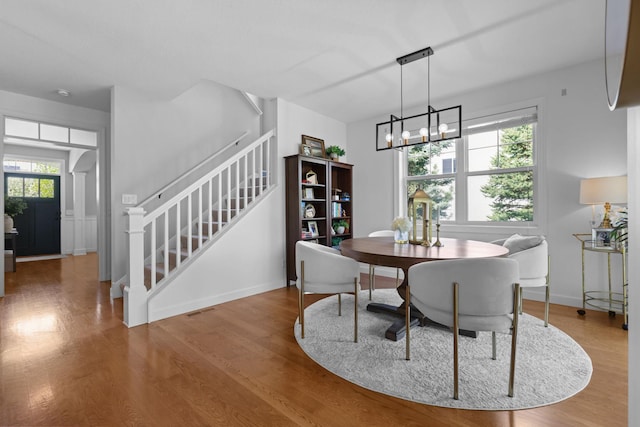 11464 Wagon Wheel Curv, Woodbury, MN 55129 - dining area featuring stairway, wood finished floors, a chandelier, and baseboards