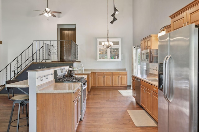 7900 Idaho Cir N, Brooklyn Park, MN 55445 - kitchen featuring appliances with stainless steel finishes, a high ceiling, light wood-style flooring, a breakfast bar, and light countertops