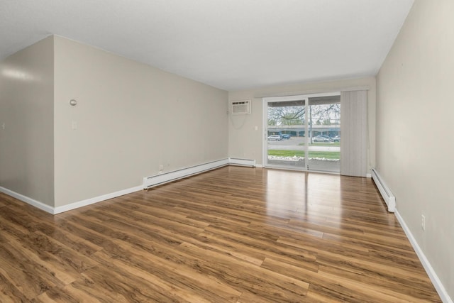 spare room featuring a baseboard heating unit, wood finished floors, a wall mounted air conditioner, and baseboards