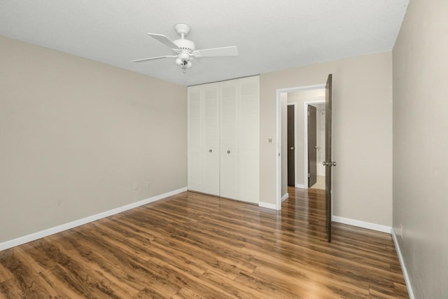 unfurnished bedroom featuring wood finished floors, a closet, and baseboards