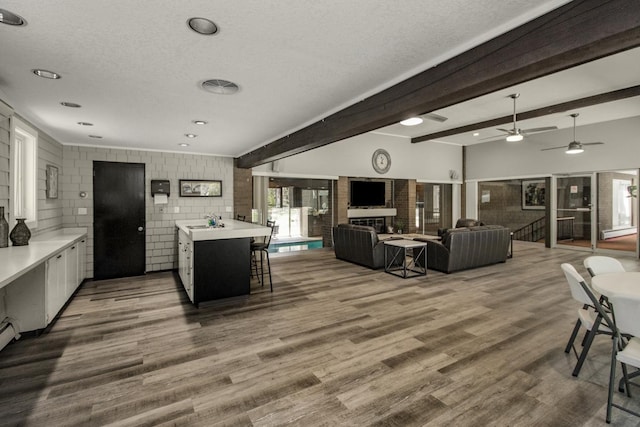 kitchen with light countertops, a sink, wood finished floors, a textured ceiling, and a kitchen breakfast bar