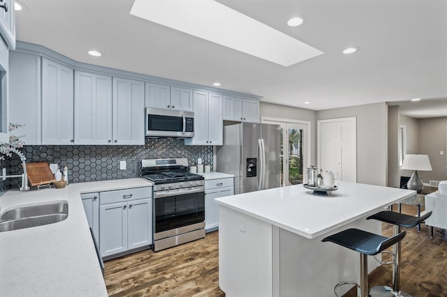 25985 Smithtown Rd, Shorewood, MN 55331 - kitchen featuring appliances with stainless steel finishes, a skylight, dark wood-style flooring, a center island, and recessed lighting