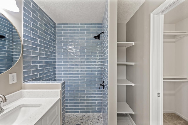 25985 Smithtown Rd, Shorewood, MN 55331 - bathroom featuring tiled shower, a walk in closet, vanity, and a textured ceiling