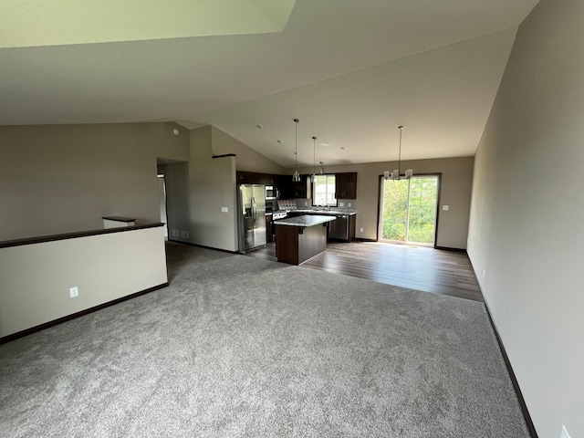 kitchen featuring lofted ceiling, open floor plan, a kitchen island, dark carpet, and stainless steel appliances