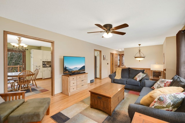 living room with light wood-type flooring and ceiling fan with notable chandelier