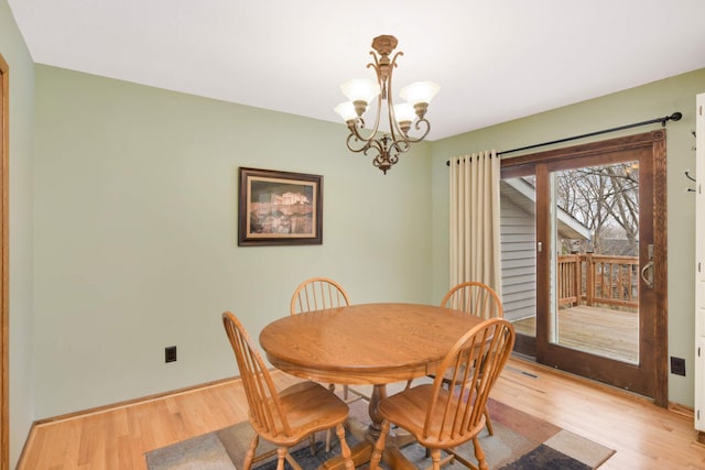 dining space with light wood finished floors, a chandelier, and baseboards