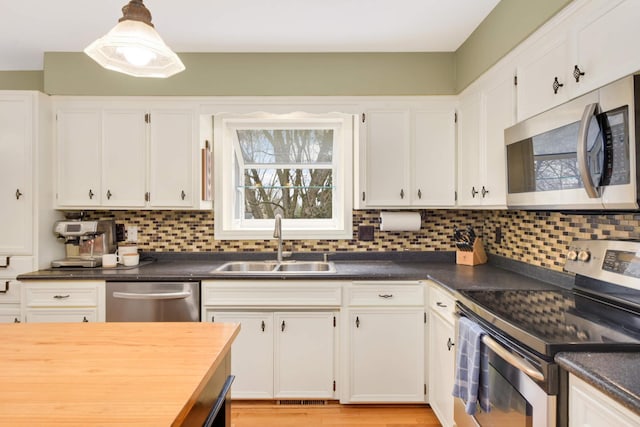 kitchen featuring white cabinets, stainless steel appliances, tasteful backsplash, and a sink