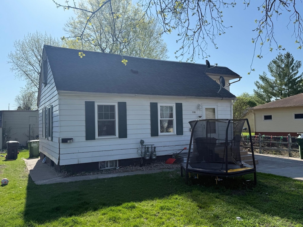 rear view of house with a trampoline, central AC unit, and a shingled roof