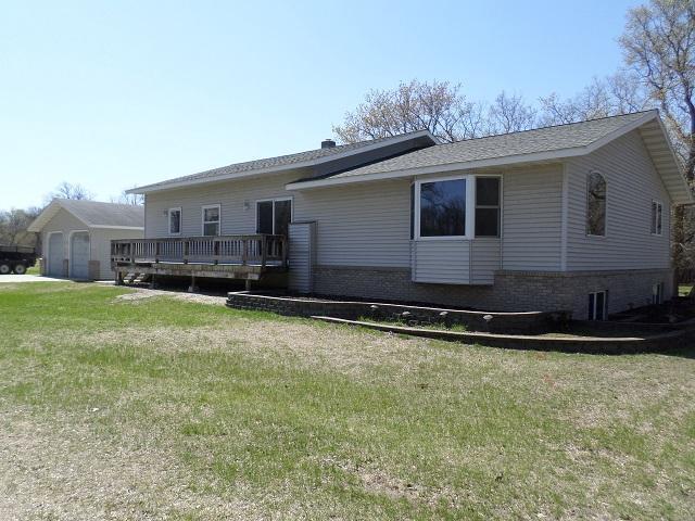202 Buse Ave NE, Red Lake Falls, MN 56750 - back of house featuring a lawn, a deck, brick siding, and a garage