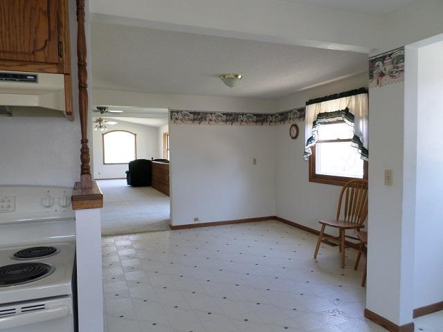 202 Buse Ave NE, Red Lake Falls, MN 56750 - interior space with brown cabinets, a ceiling fan, light floors, under cabinet range hood, and white electric range