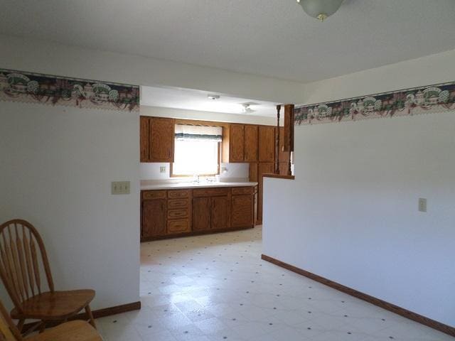 202 Buse Ave NE, Red Lake Falls, MN 56750 - kitchen featuring light floors, brown cabinetry, baseboards, a sink, and light countertops