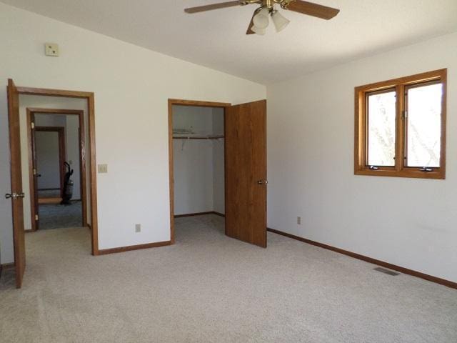 202 Buse Ave NE, Red Lake Falls, MN 56750 - unfurnished bedroom featuring a closet, vaulted ceiling, light carpet, a ceiling fan, and baseboards