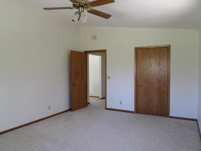 202 Buse Ave NE, Red Lake Falls, MN 56750 - unfurnished bedroom with vaulted ceiling, light colored carpet, baseboards, and a ceiling fan