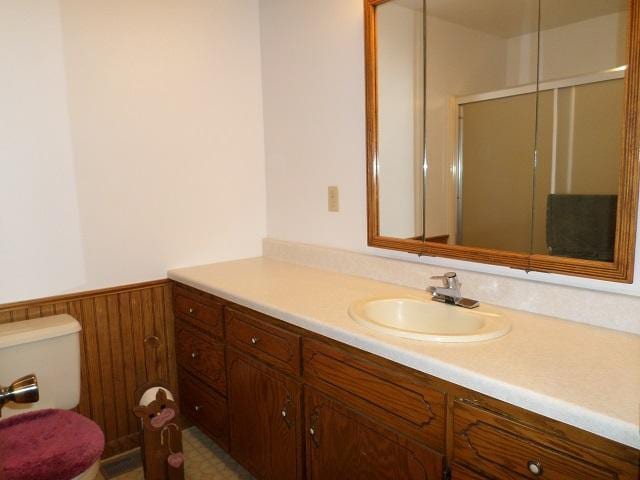 202 Buse Ave NE, Red Lake Falls, MN 56750 - full bathroom featuring toilet, a wainscoted wall, a shower with door, wooden walls, and vanity