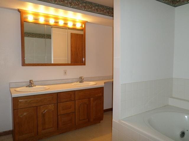 202 Buse Ave NE, Red Lake Falls, MN 56750 - bathroom featuring a garden tub, double vanity, and a sink