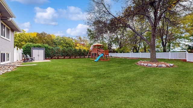 view of yard featuring a fenced backyard, an outdoor structure, a playground, and a shed