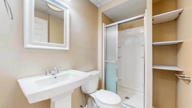 bathroom with toilet, a shower stall, and a sink