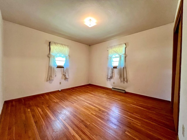 unfurnished room with plenty of natural light, hardwood / wood-style floors, and baseboard heating