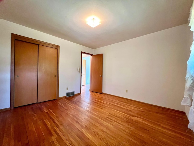 unfurnished bedroom with light wood-style floors, a closet, and baseboards