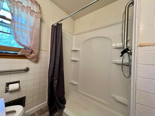 bathroom with a shower stall, tile walls, and toilet