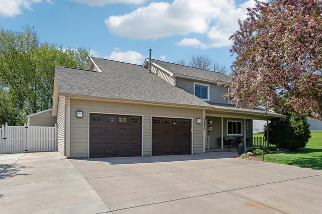 view of front of property with a gate, concrete driveway, a porch, a shingled roof, and an attached garage