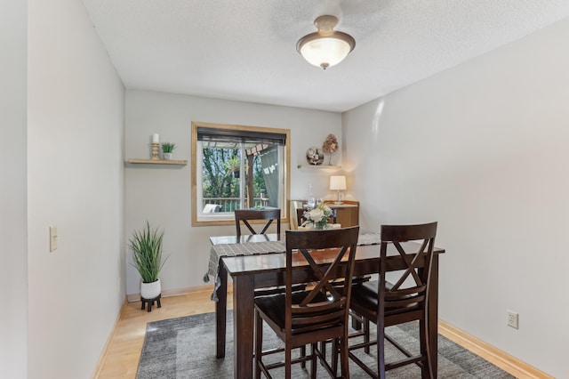 dining area with baseboards, a textured ceiling, and wood finished floors