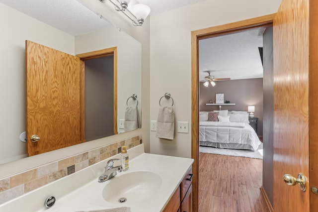 bathroom featuring connected bathroom, vanity, a textured ceiling, a ceiling fan, and wood finished floors