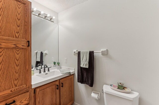 bathroom with toilet, a textured ceiling, and vanity