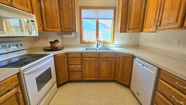 kitchen featuring white appliances, a sink, brown cabinetry, and light countertops