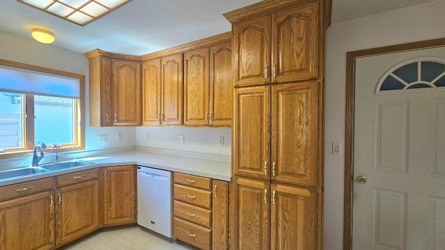kitchen with white dishwasher, a sink, brown cabinetry, and light countertops