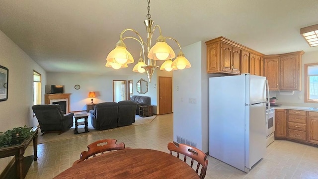 kitchen featuring white appliances, a chandelier, open floor plan, a fireplace, and light countertops