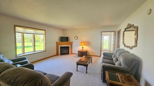 living area with light carpet, baseboards, a fireplace with flush hearth, and a textured ceiling